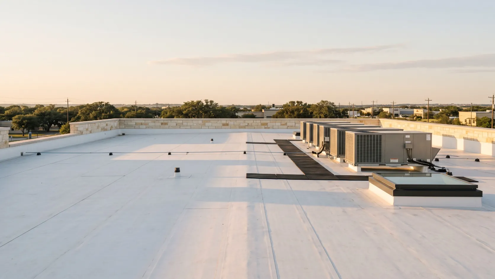 The membrane roof, parapet and HVAC units of a Texas commercial building at golden hour